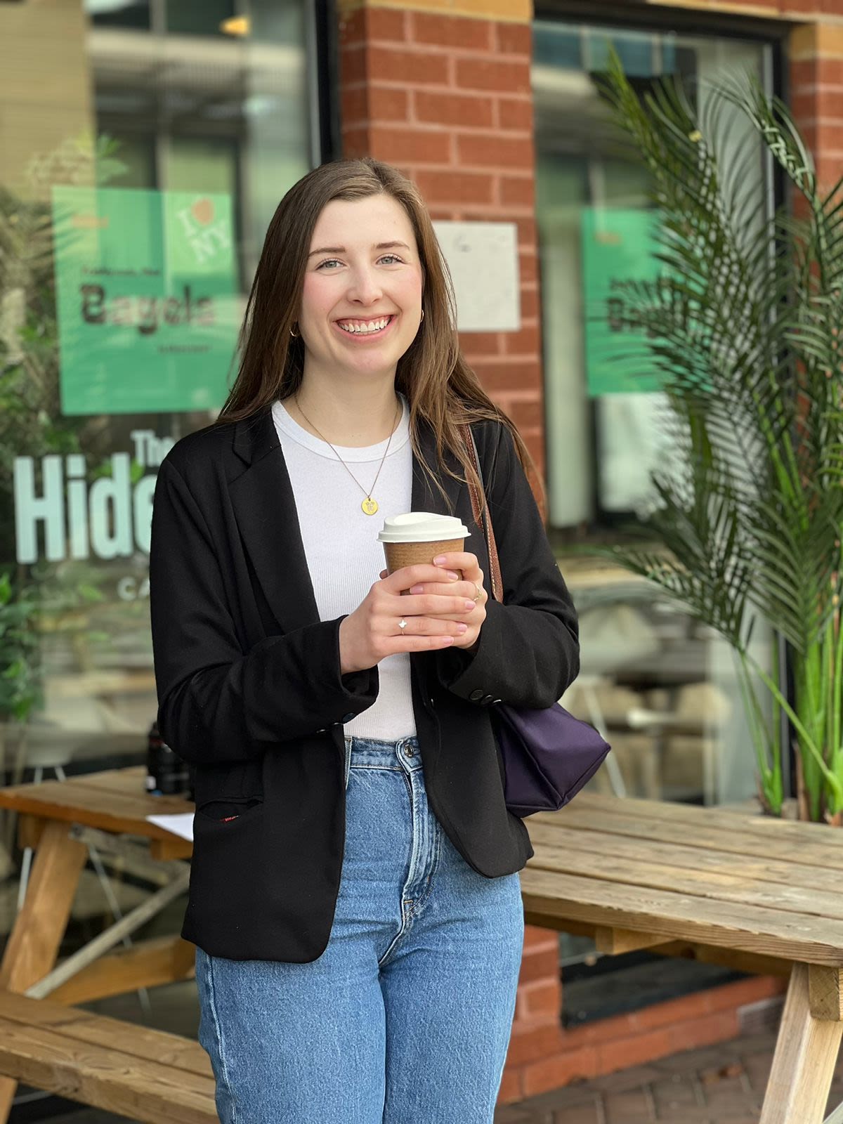 Reagan Martin holds a cup of coffee outside The Hideout Cafe 
