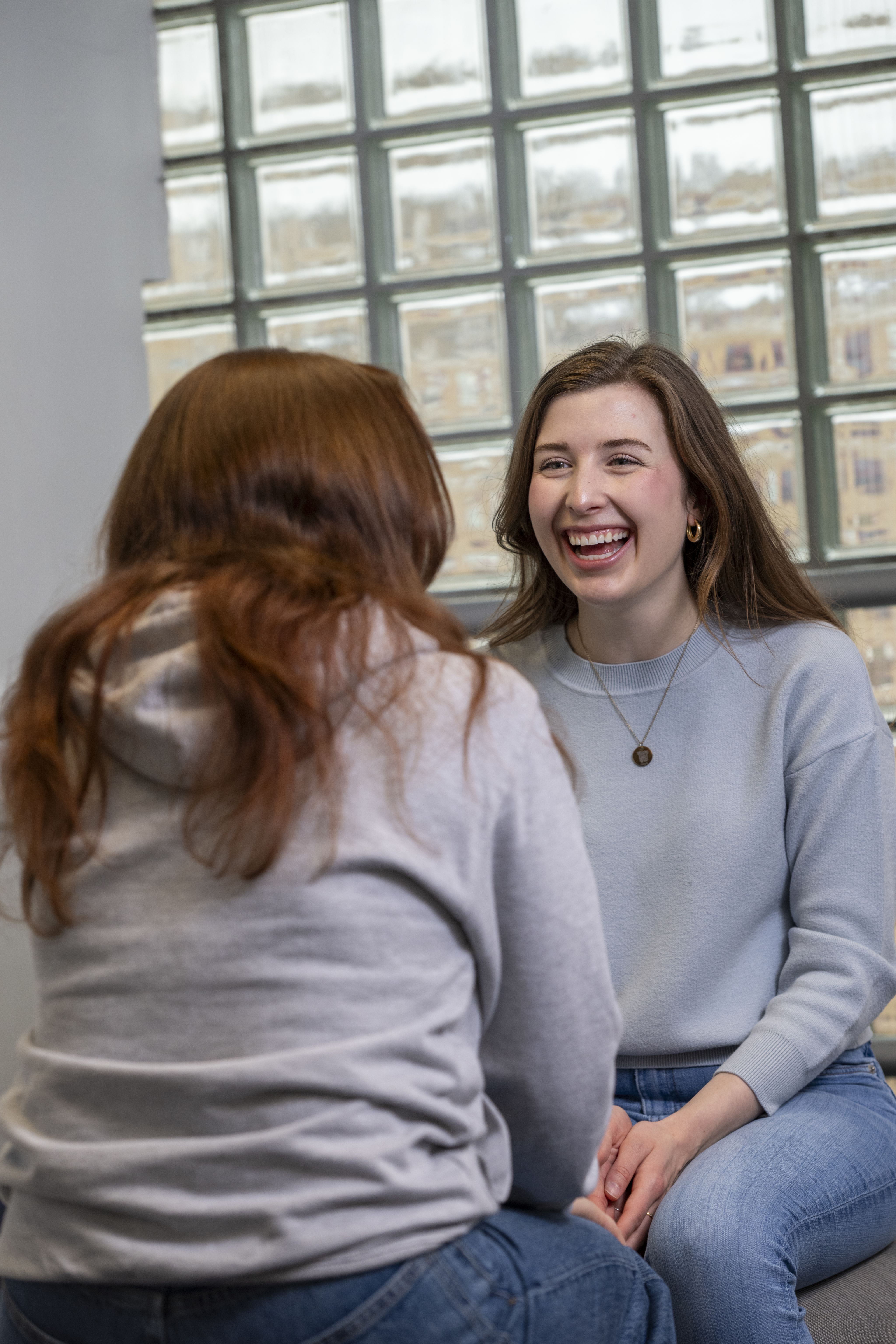 Reagan laughs as she chats to a fellow student in the library