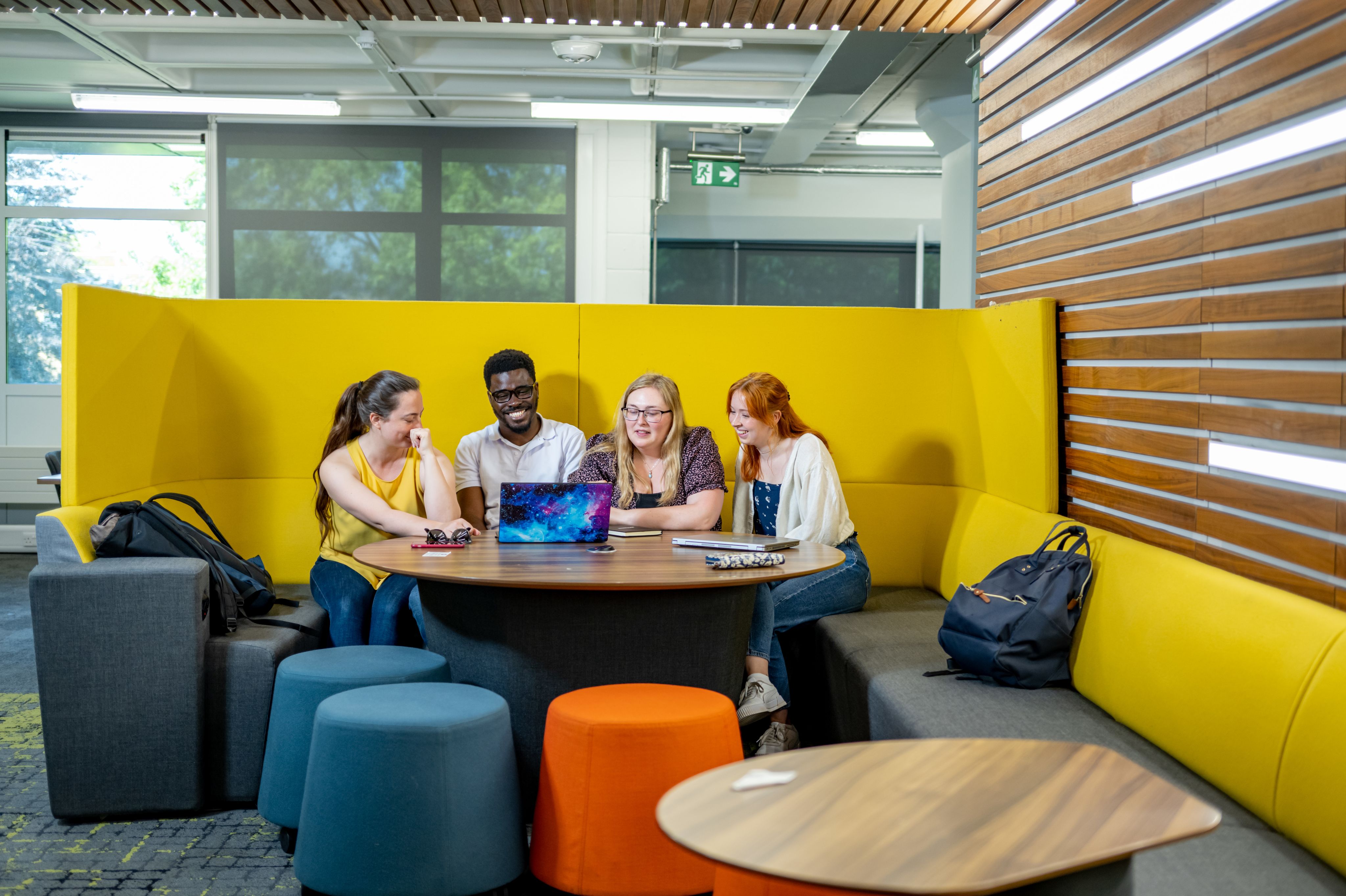 A group of students look at a laptop in the University library
