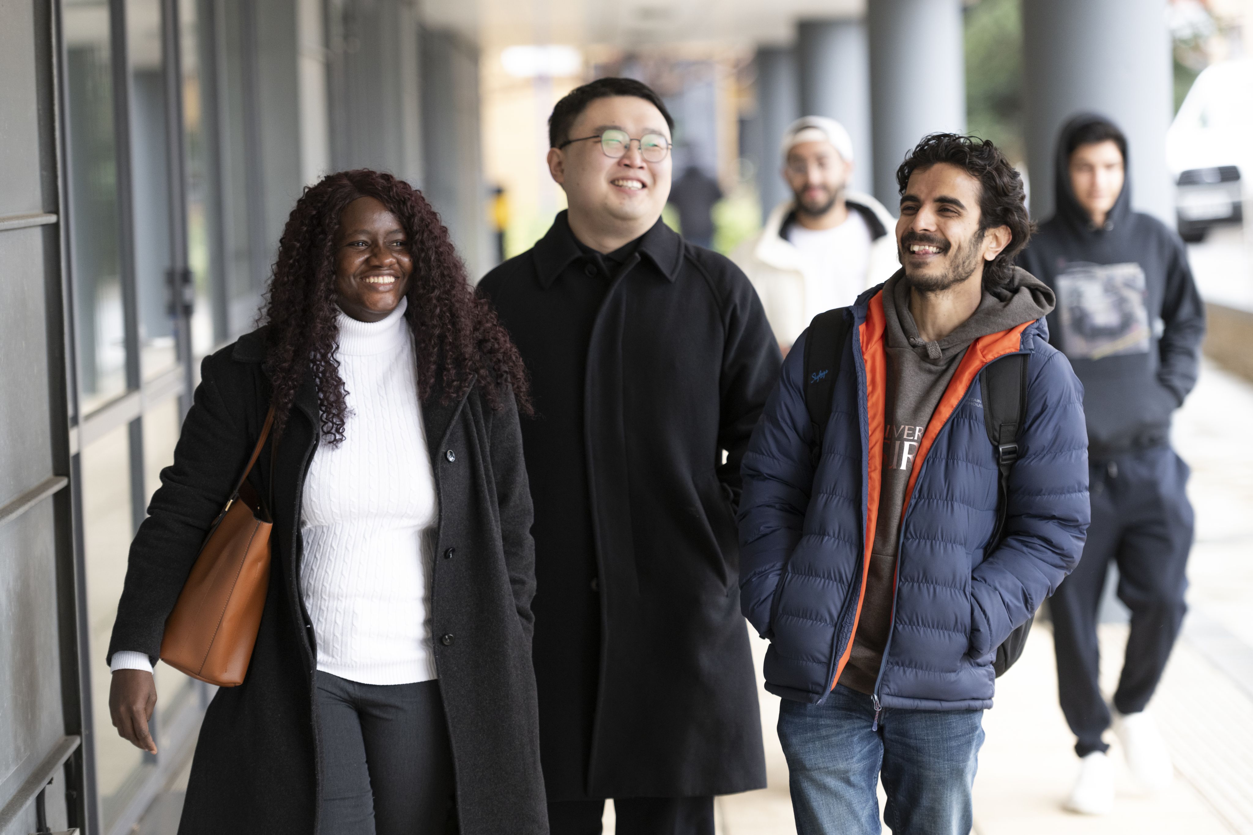 Three international students walk past Surrey Business School