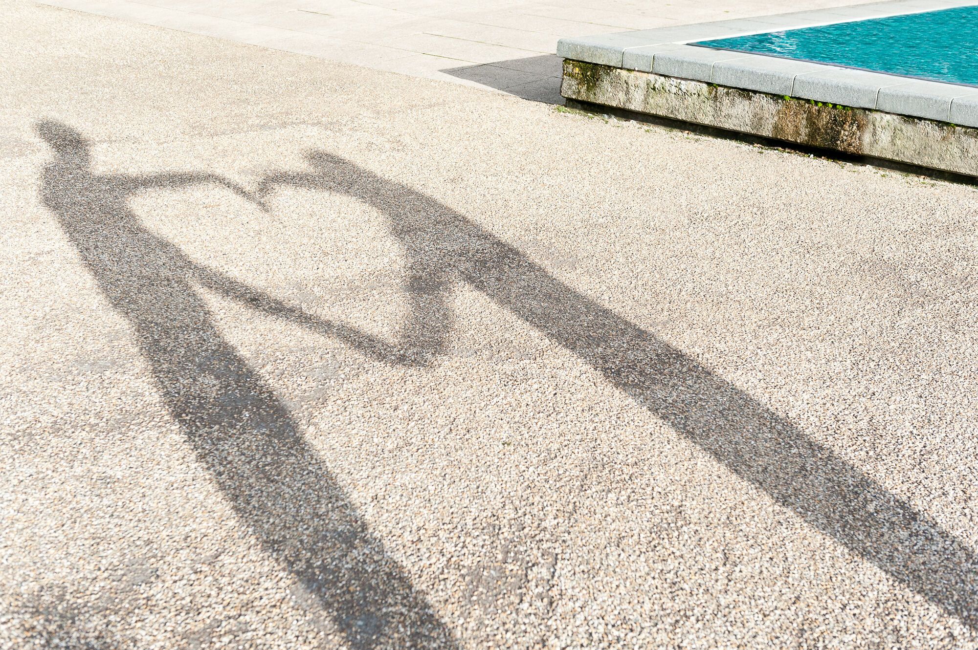 A shadow of two people making a heart shape with their arms