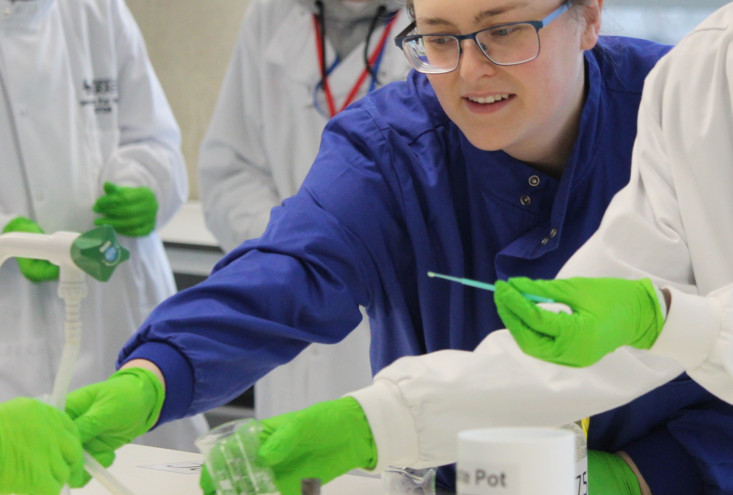 Students with pipets in lab coats and gloves
