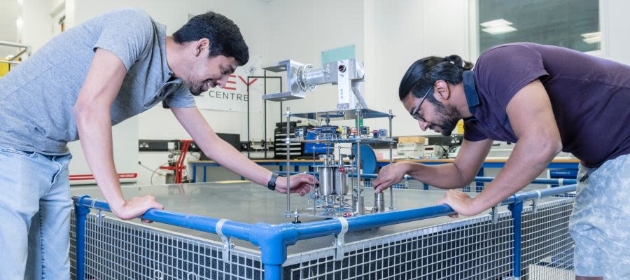 Two men operate machinery on the granite table in Surrey Space Centre