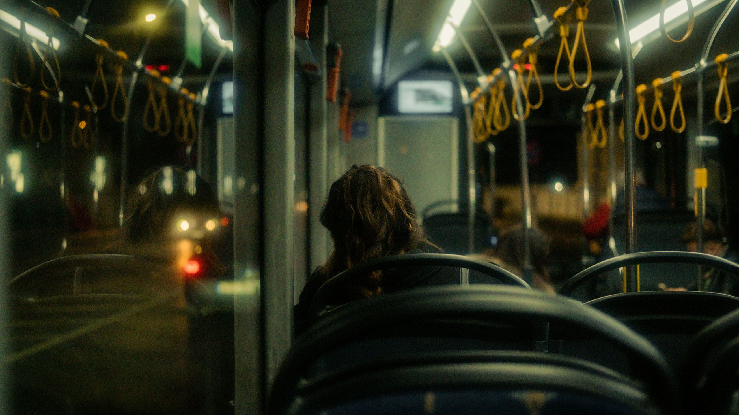 a female sits alone on a bus at night