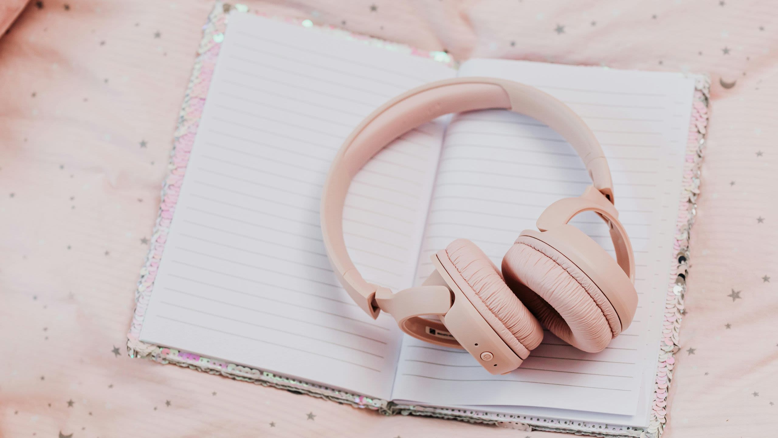 A pair of pink headphones on a blank notebook