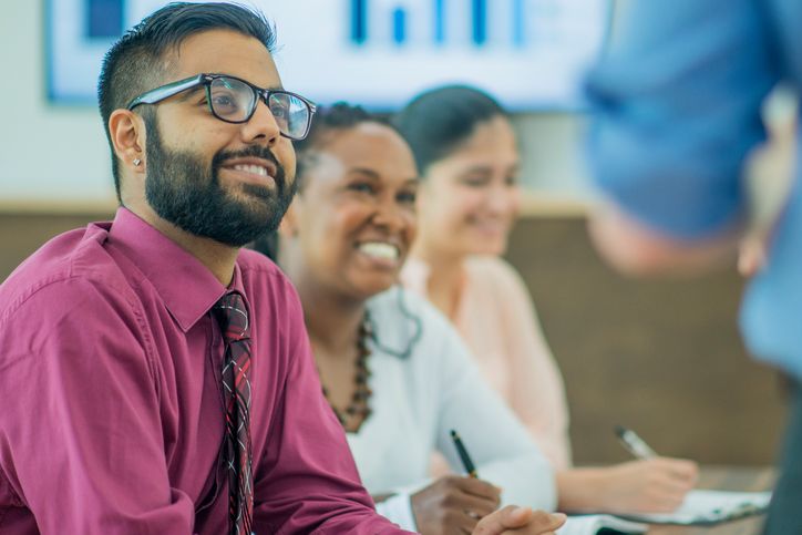 people sitting on chair in front of table while holding pens during daytime