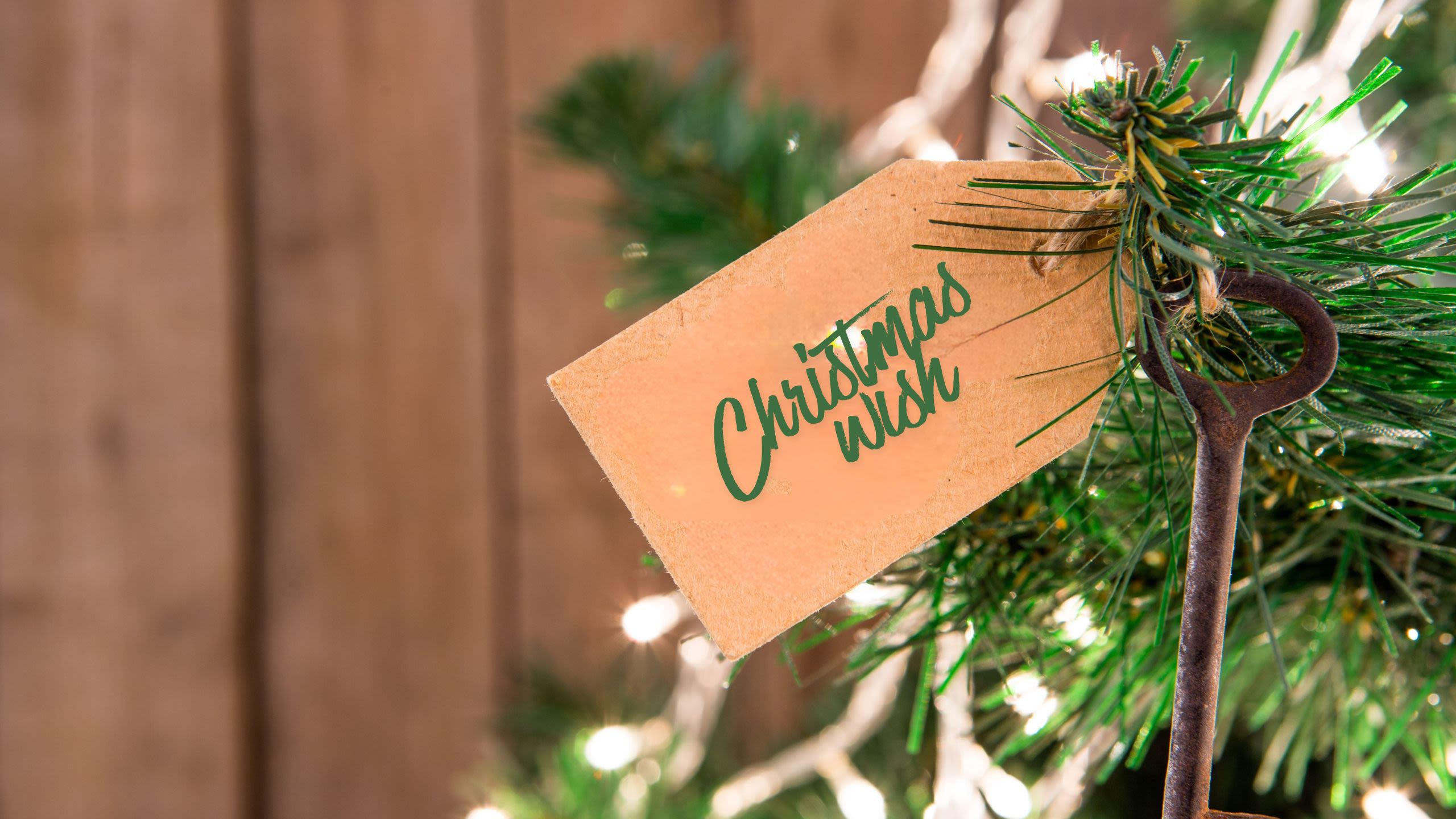 A brown paper tag with the inscription "Christmas wish" is tied to a Christmas tree