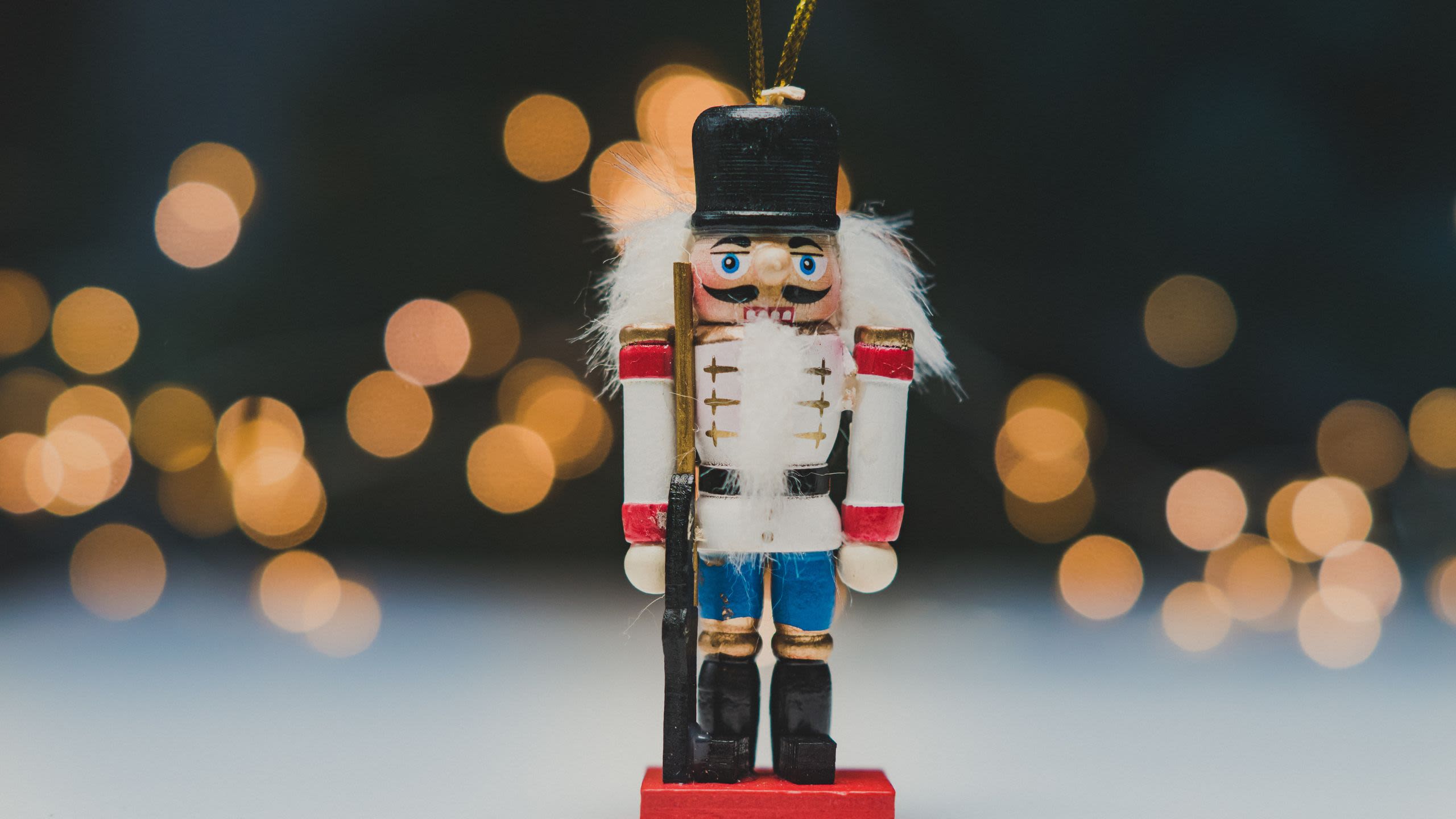 A nutcracker ornament with a background of twinkly lights